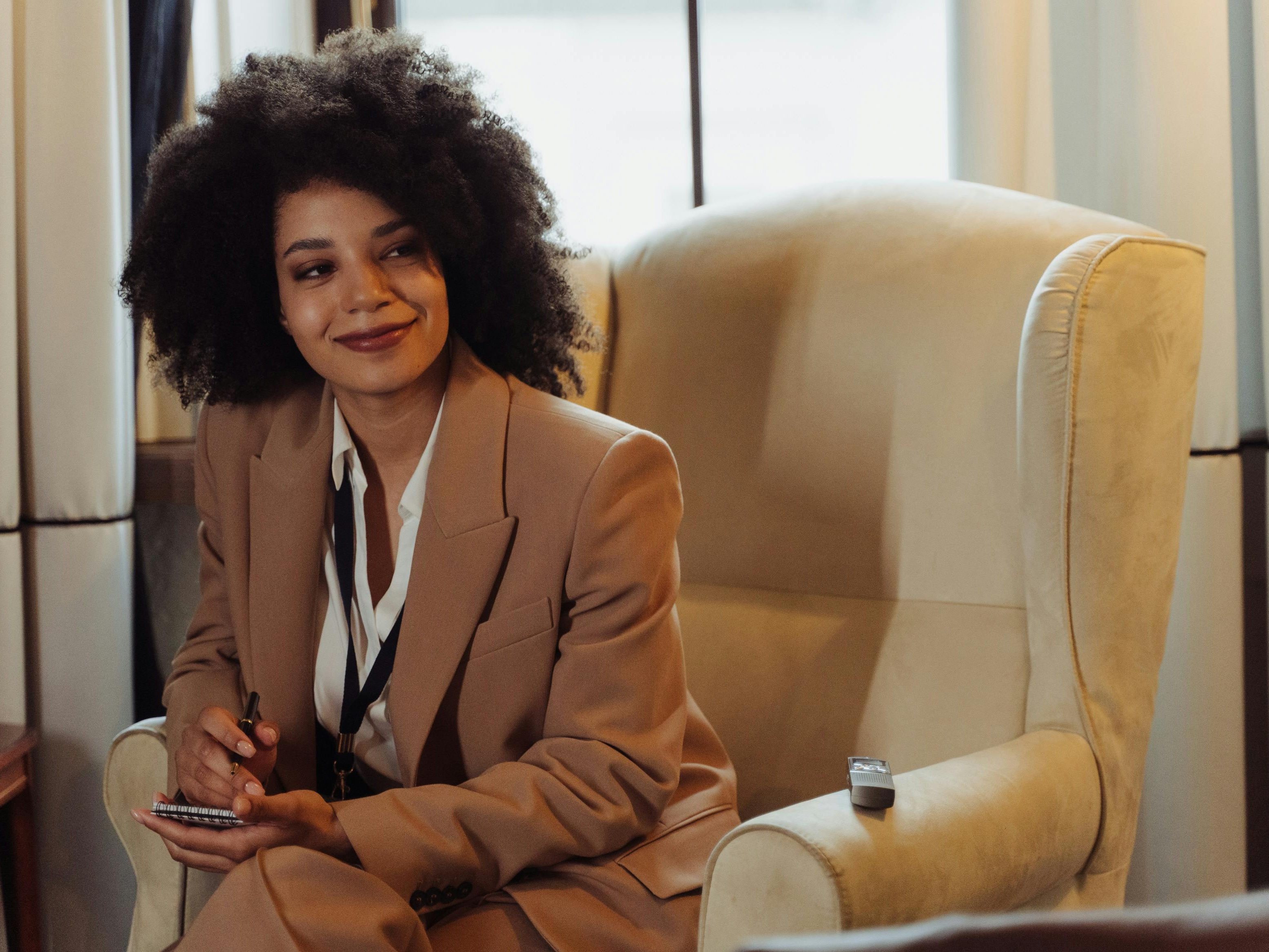 Student Nes Agopome smiles at the camera while sitting in a yellow-walled classroom.